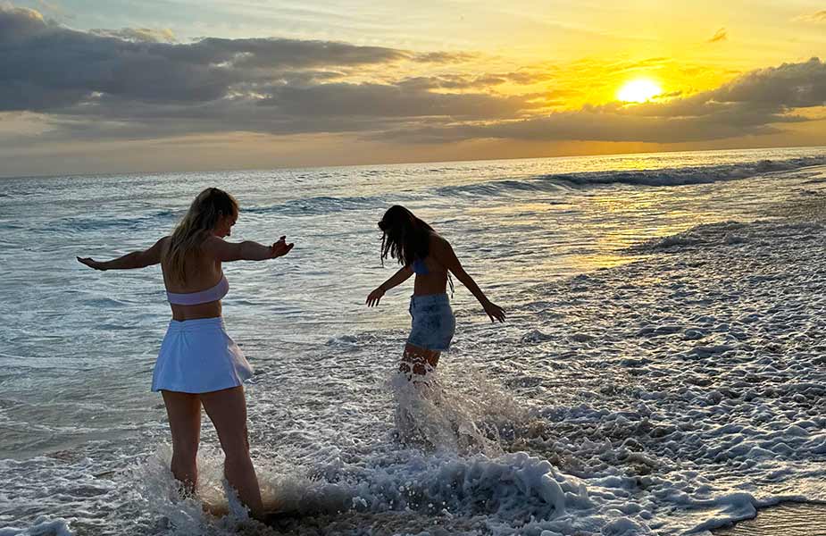 Isa en Senna in zee bij zonsondergang Kaena Point