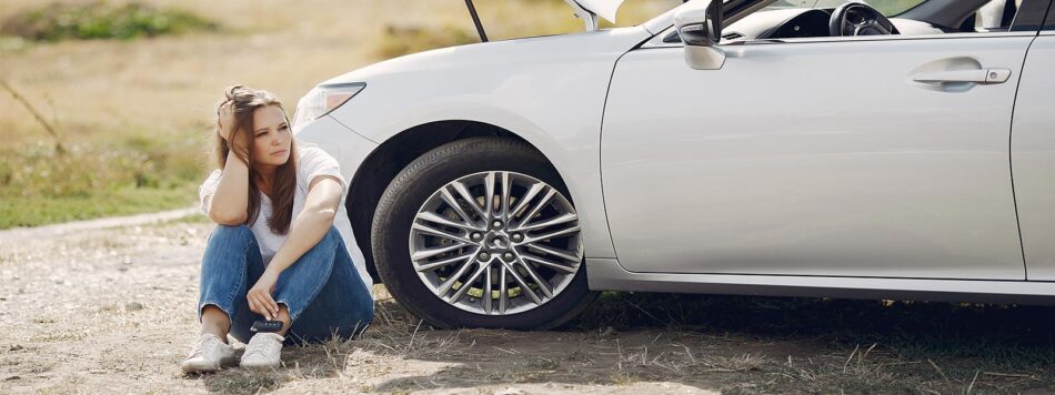 Vrouw bij auto met pech in het buitenland